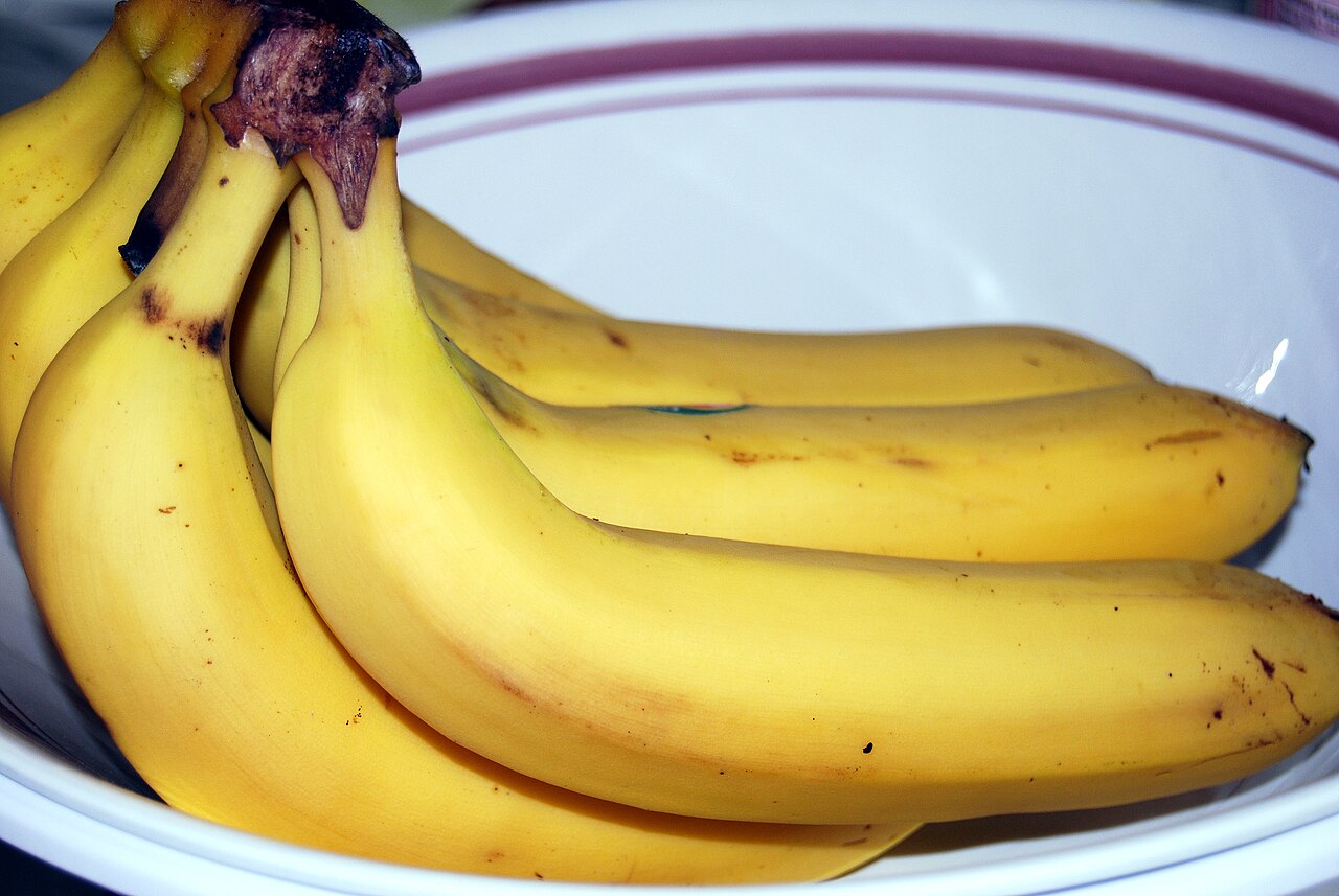 A bunch of ripe yellow bananas on a plate.