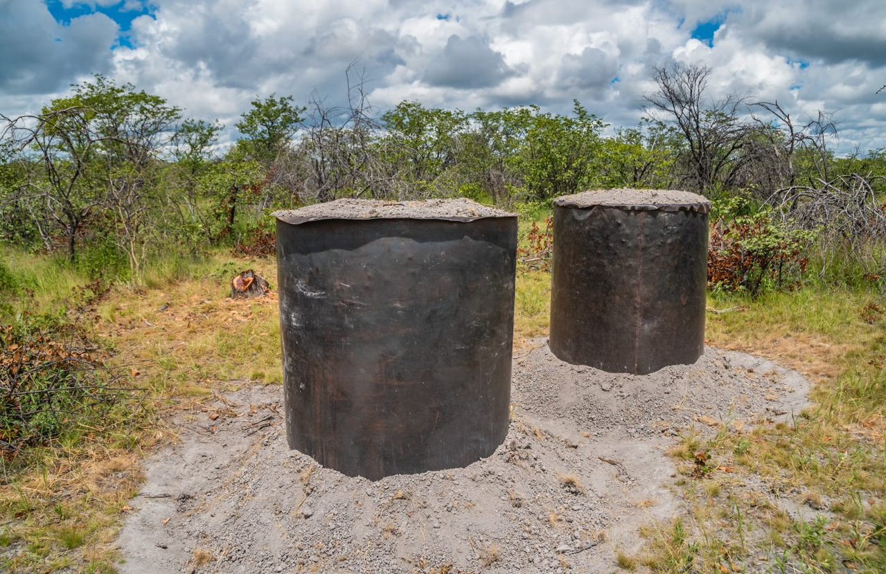 Two steel charcoal kilns positioned in the ground.