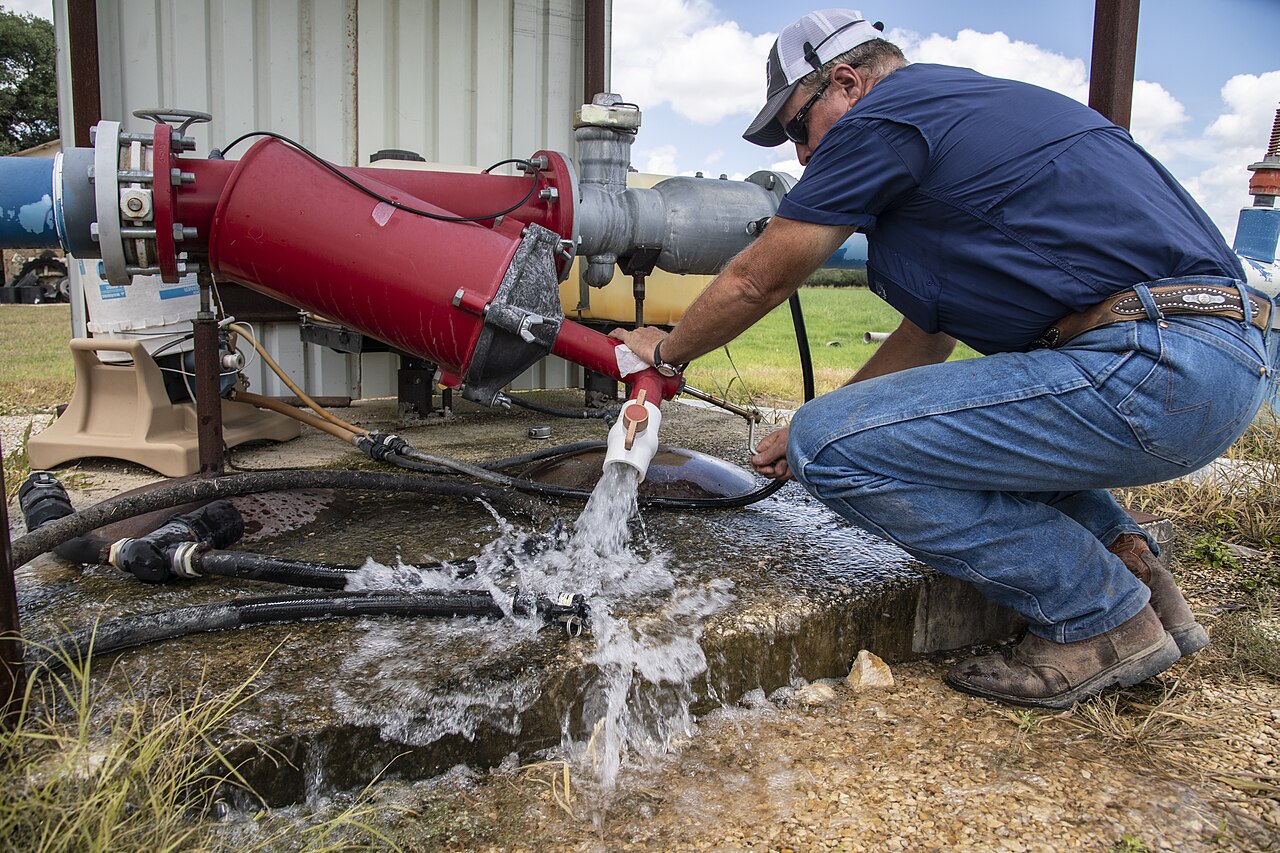 A worker inspecting water discharged from irrigation equipment.