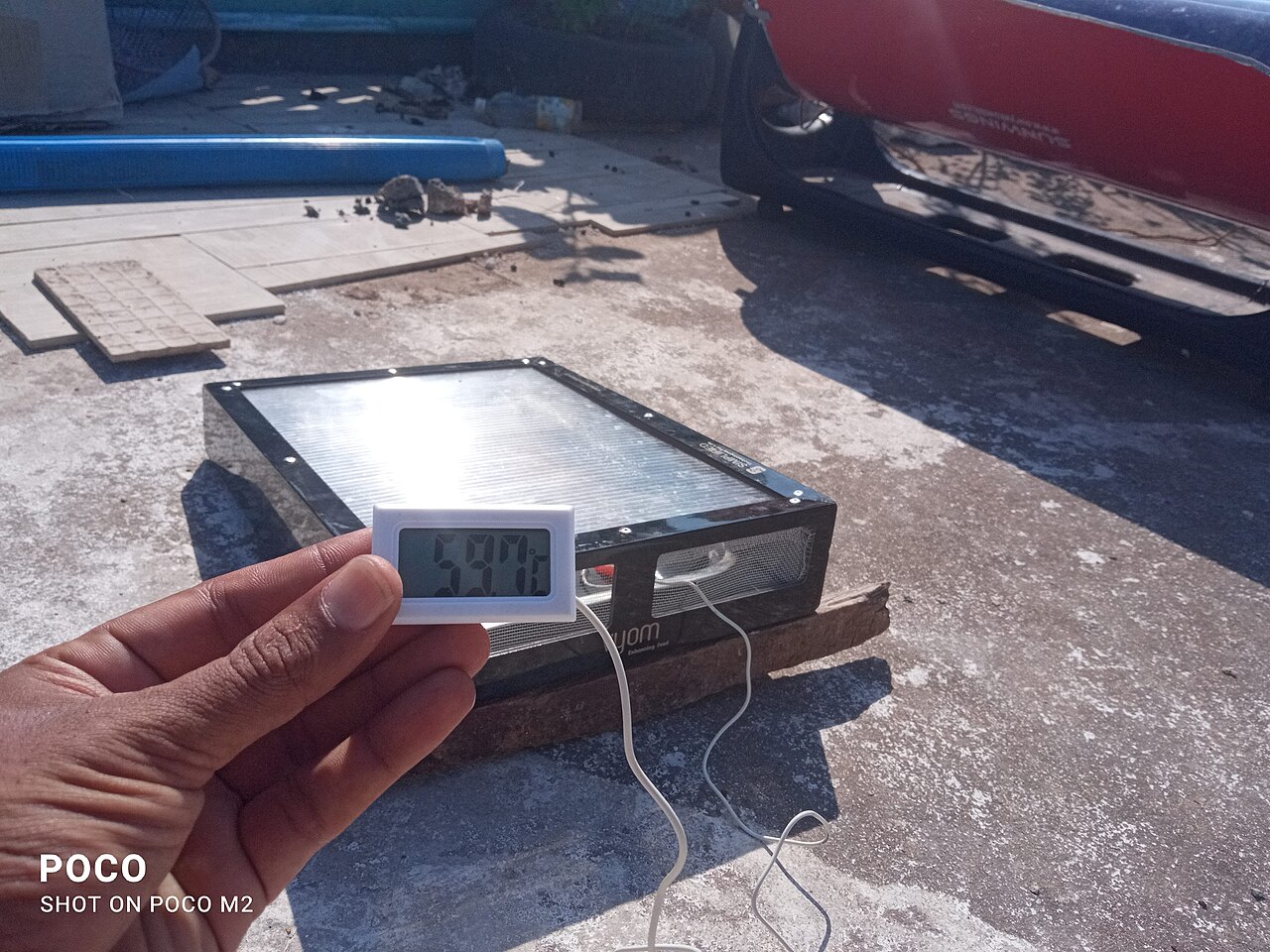 A solar-drying apparatus with a temperature reading being checked.