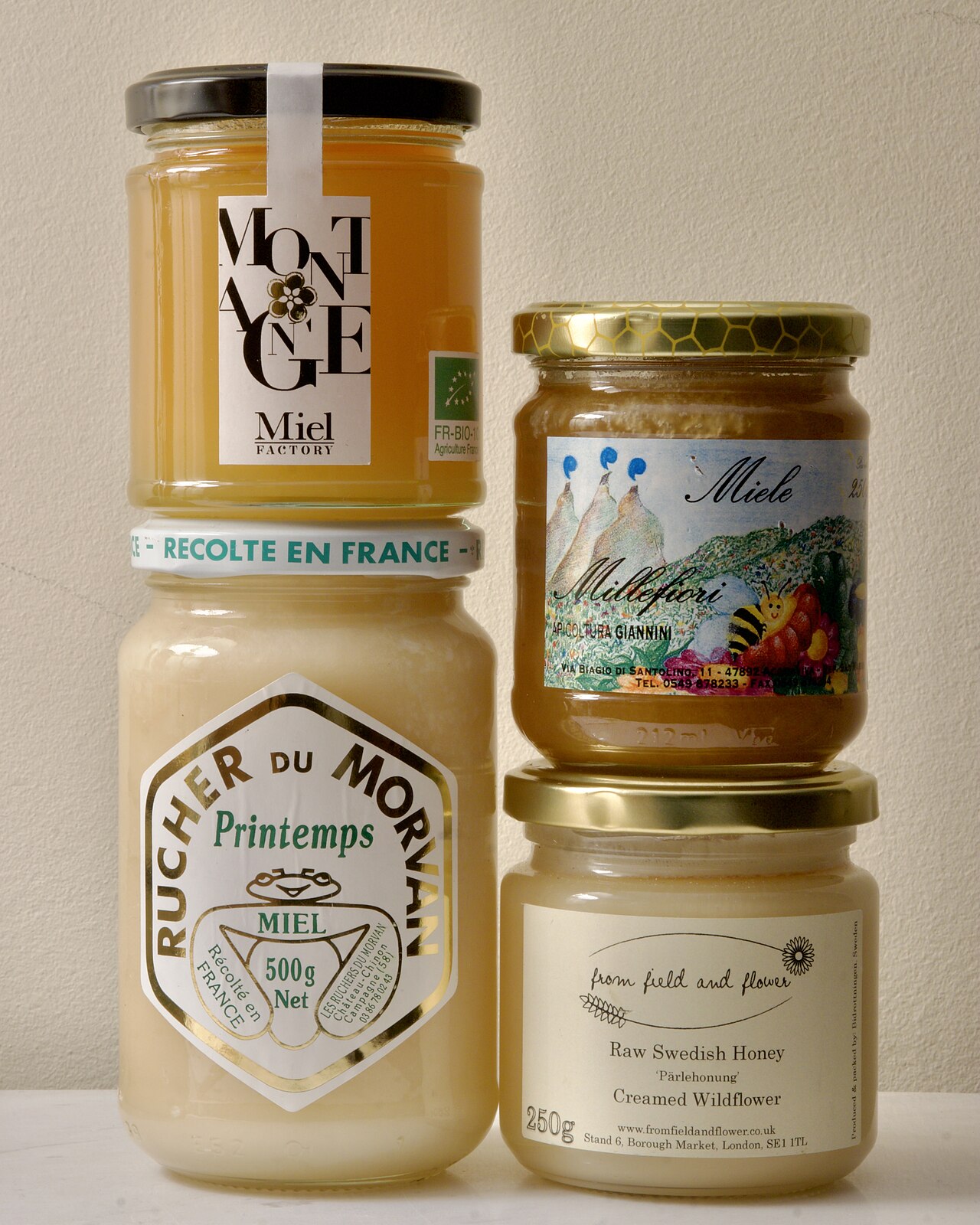 Several labelled jars of pale and golden honey.