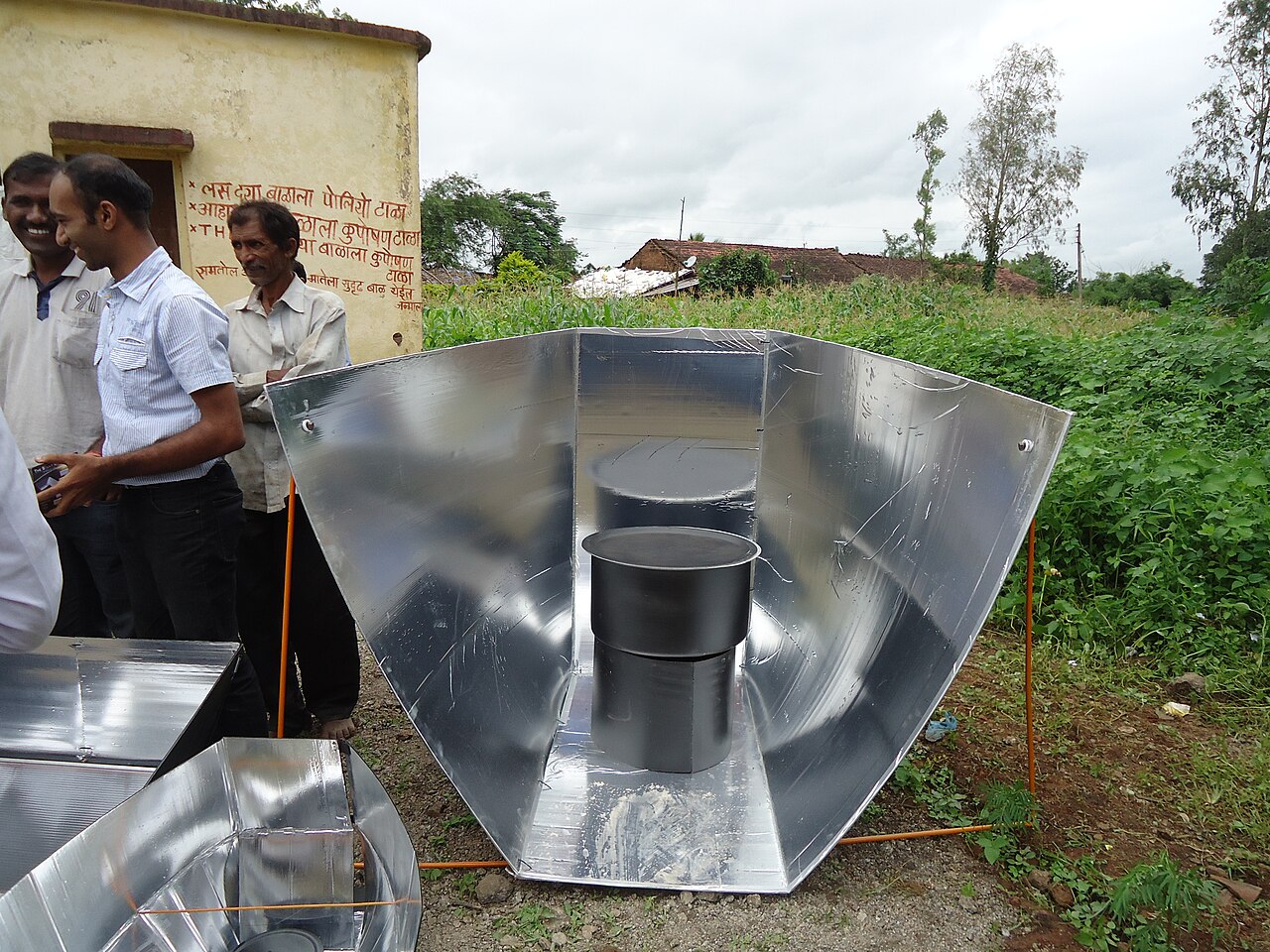Solar cooker with reflective surfaces directing sunlight toward a cooking area.