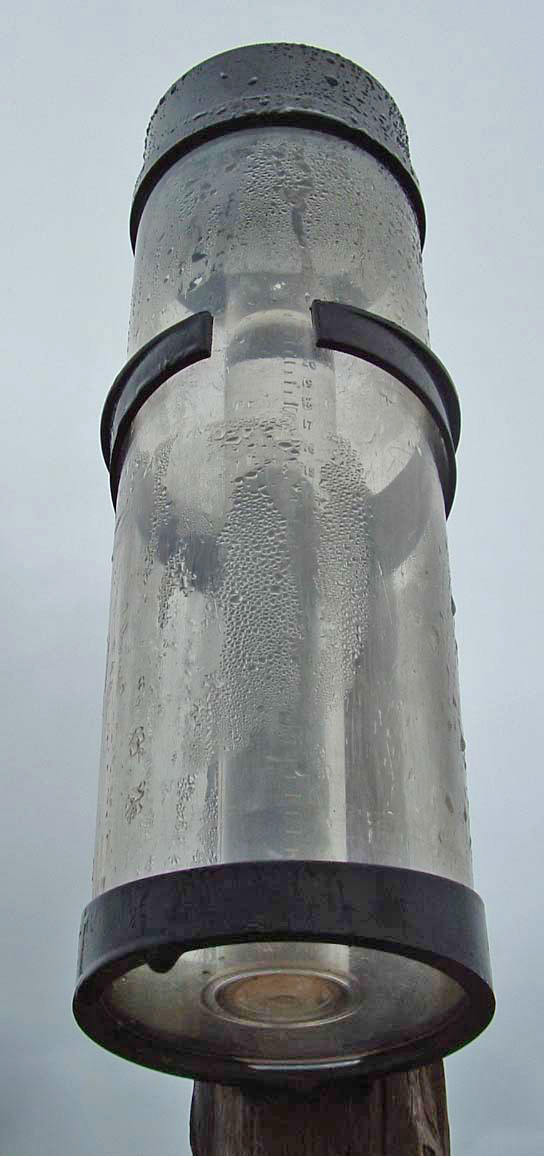 A clear plastic rain gauge with millimetre markings.